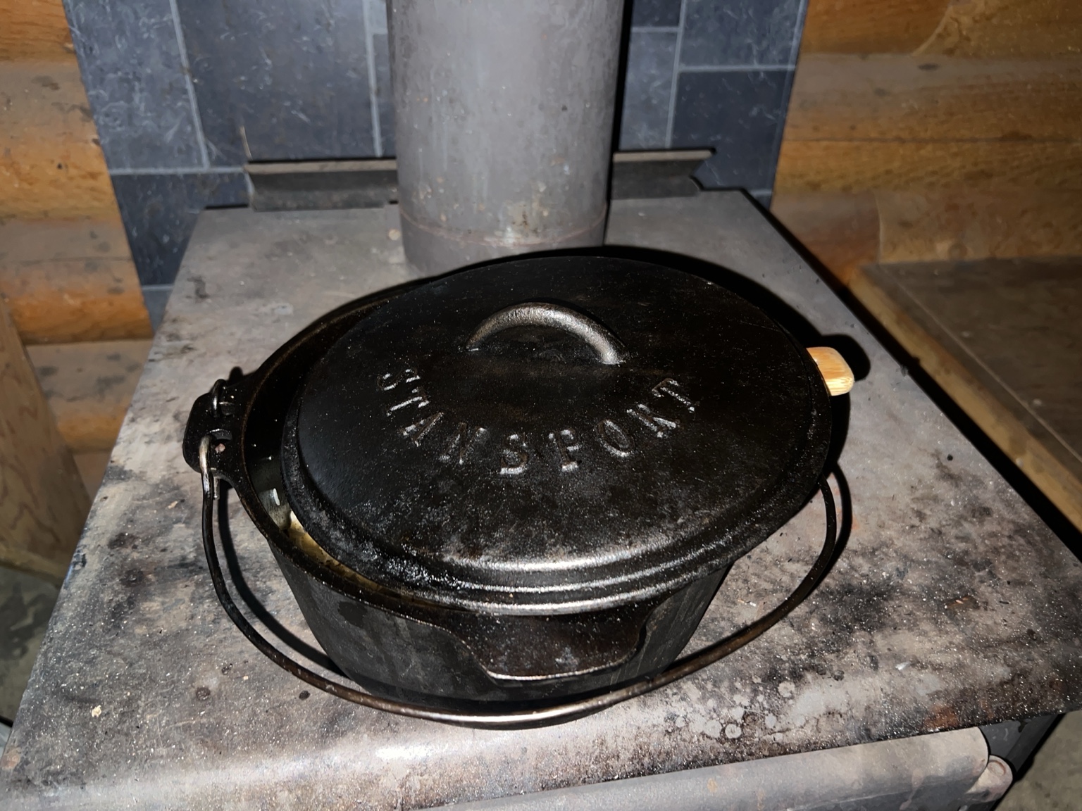Cast-iron Dutch oven resting on the cabin wood stove for a photograph