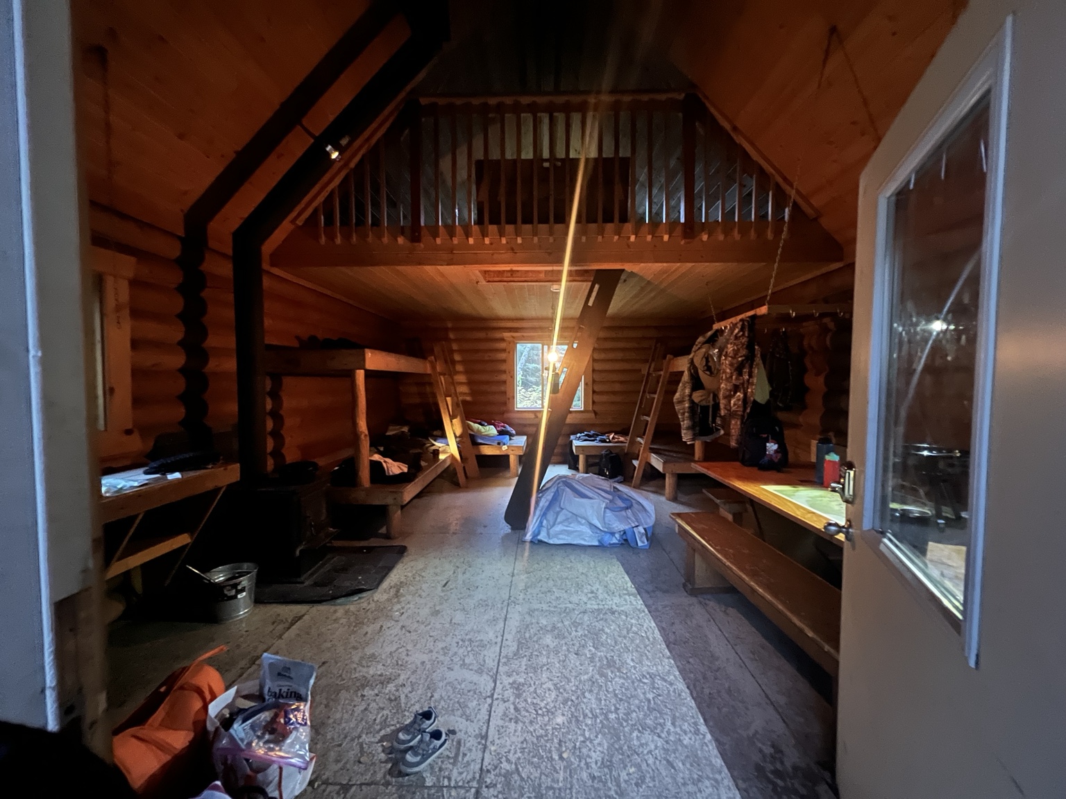 Interior of Bore Tide Cabin showing wooden bunks, loft stairs, dining area and wood stove