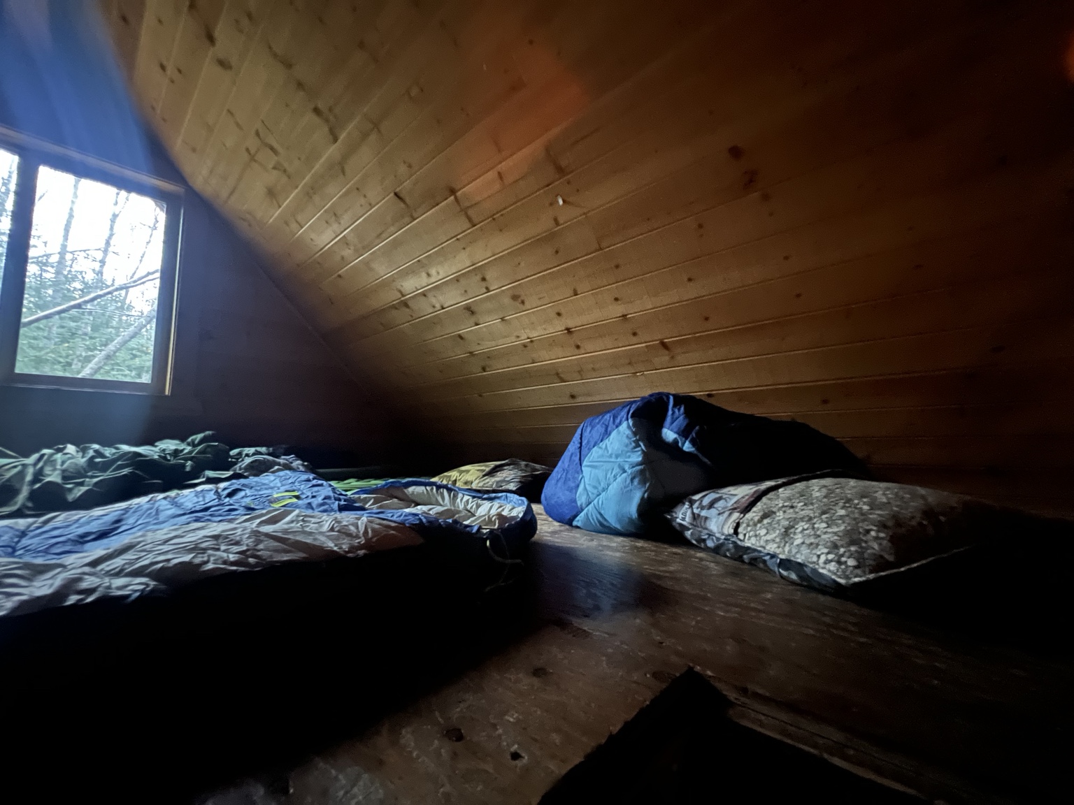 Sleeping bags spread out on the loft floor under a sloping wooden ceiling