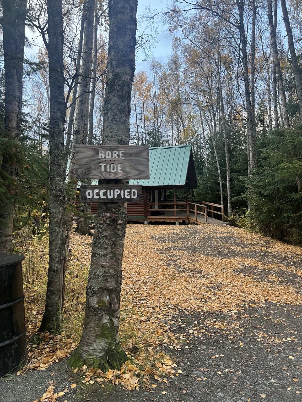 Bore Tide Cabin sign beside the cabin in an autumn forest