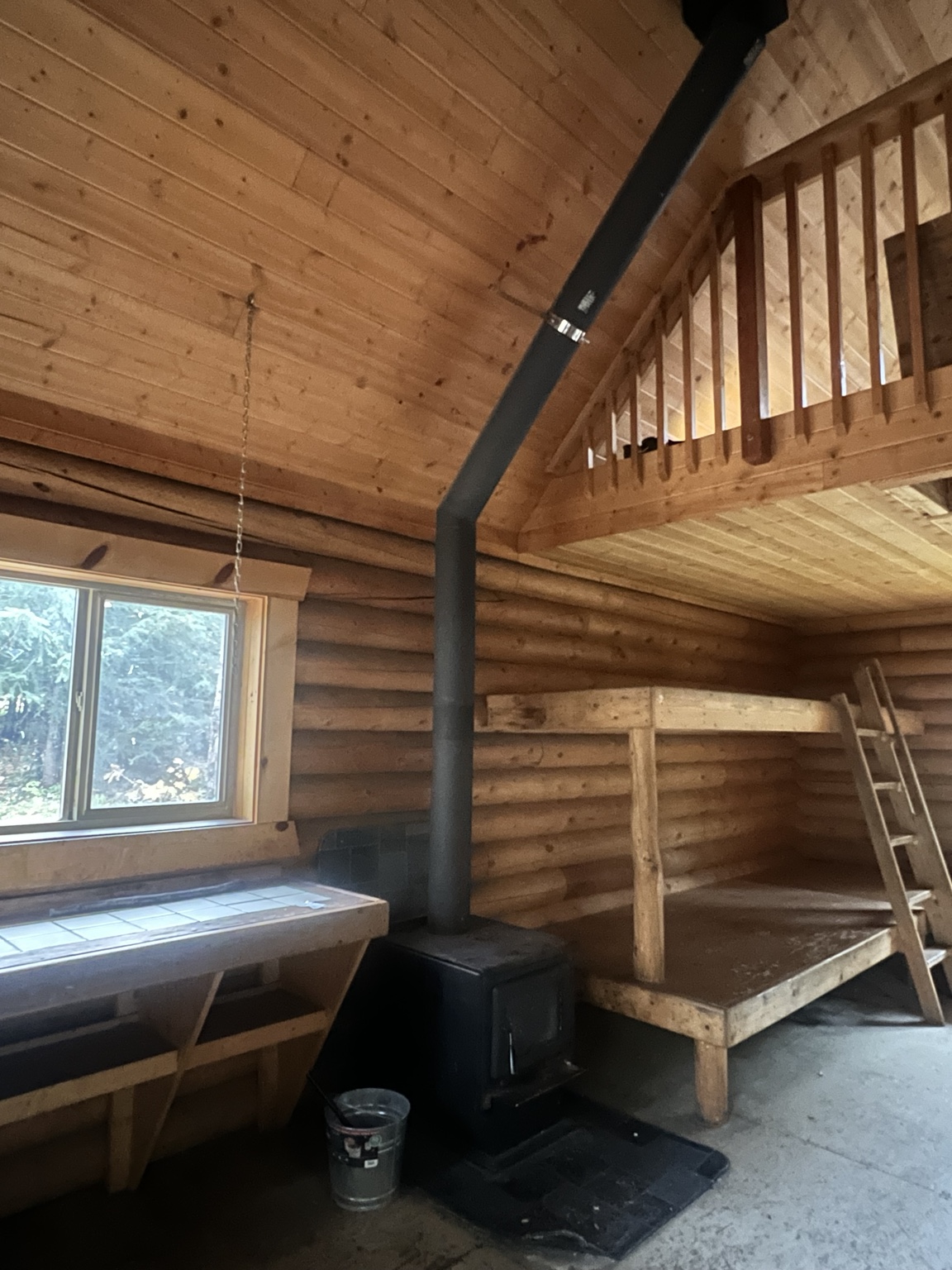 Black wood stove, chimney pipe, bunks and loft